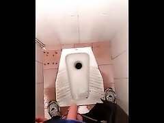 Young guy pissing in the public toilet